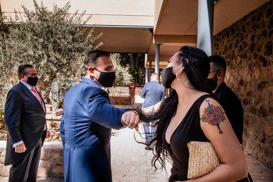 novio con mascarilla saludando con el codo