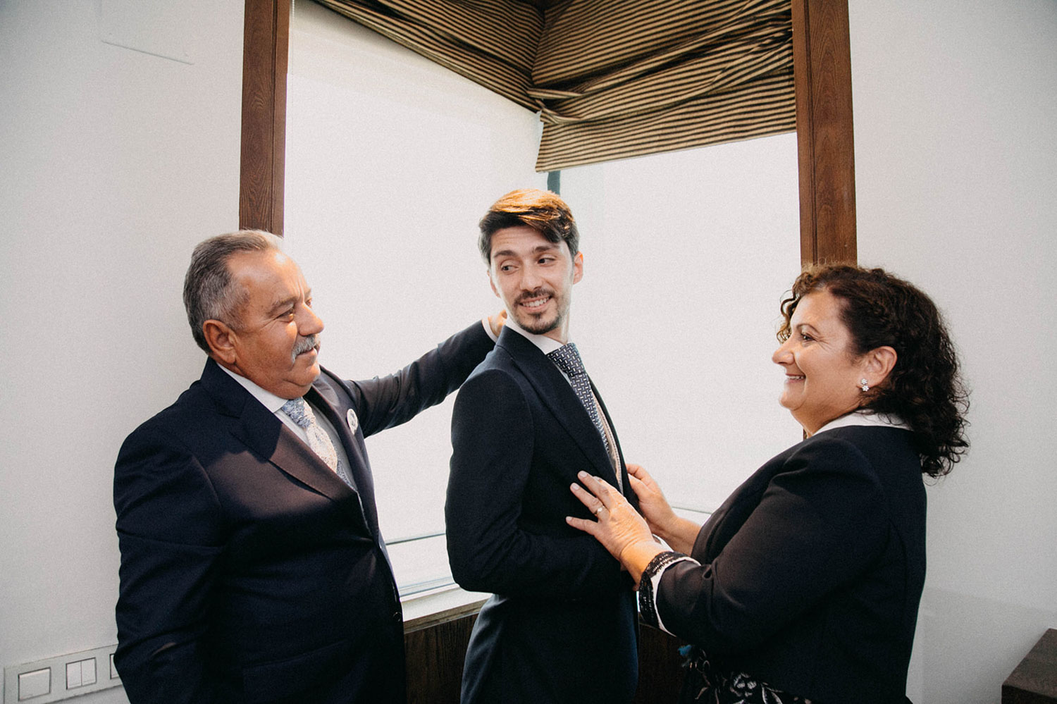 padres vistiendo a su hijo en la boda