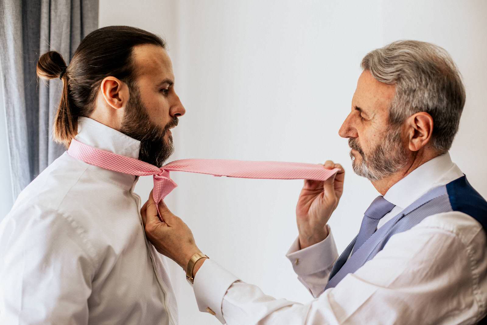 Padre ayudando a su hijo colocando la corbata en la boda