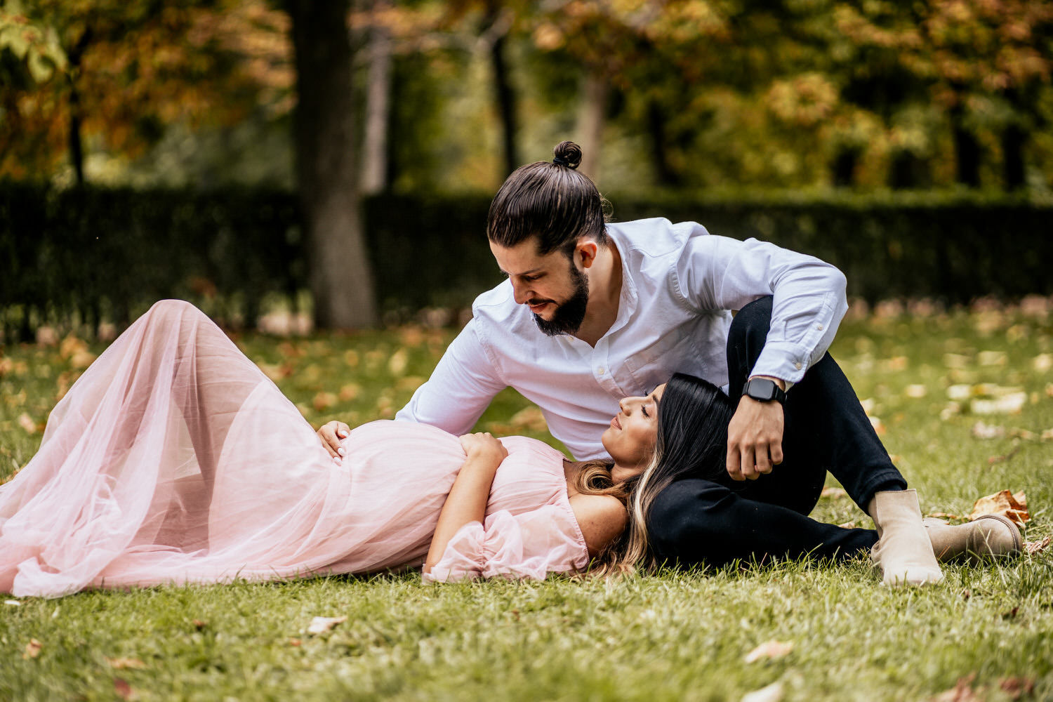 pareja recostados en el parque embarazada