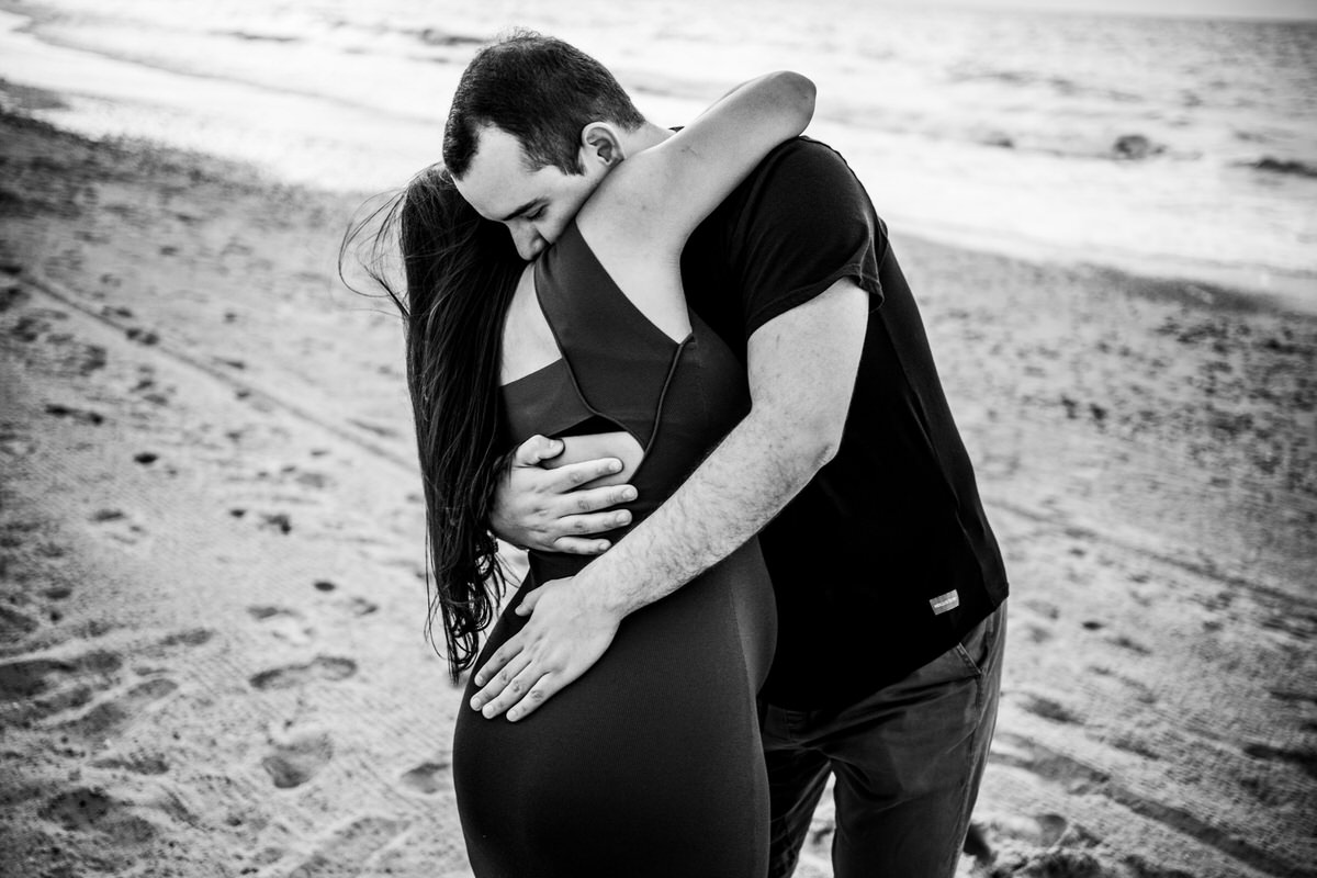 abrazo de pareja embarazada en la playa