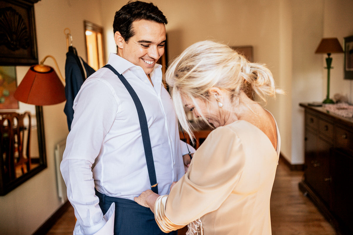 madre ayudando a su hijo a vestirse para la boda