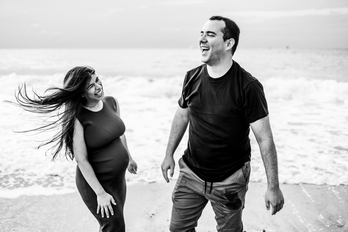 pareja embarazada con risas en la playa