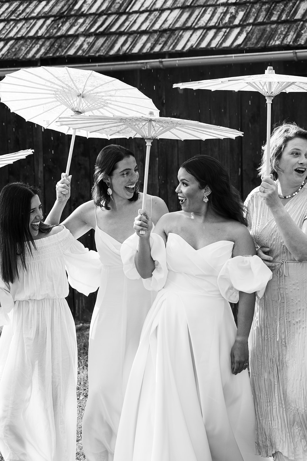 Bridesmaids posing with umbrellas during light rain