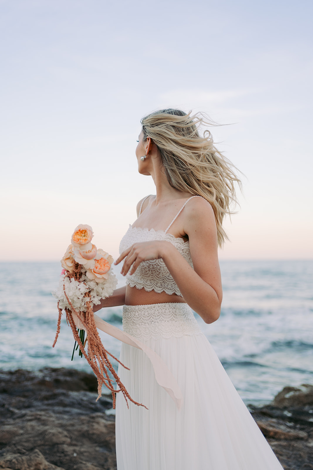 Close-up of the bride’s flowing cape with fine details, captured in the ocean breeze.