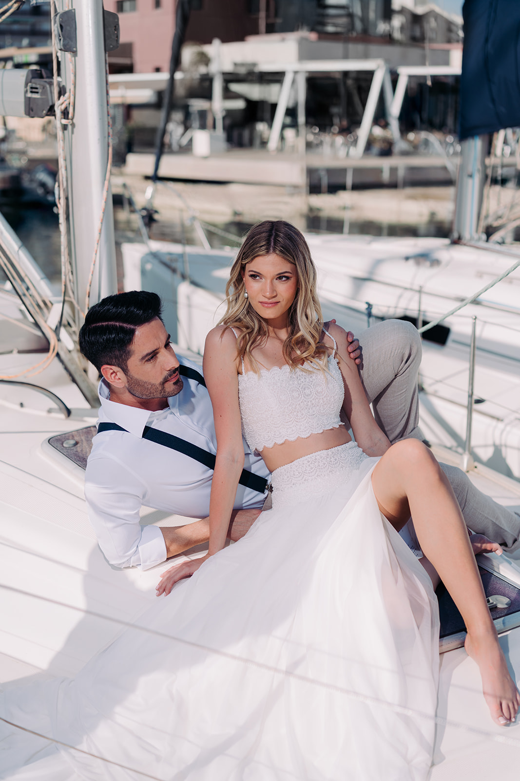 Romantic couple sitting in a boat during a Mediterranean-inspired styled shoot, surrounded by calm sea waters.