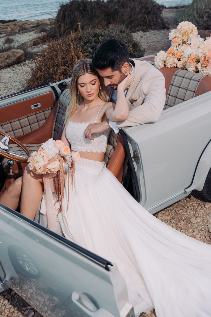 Wedding couple in classic car by the sea